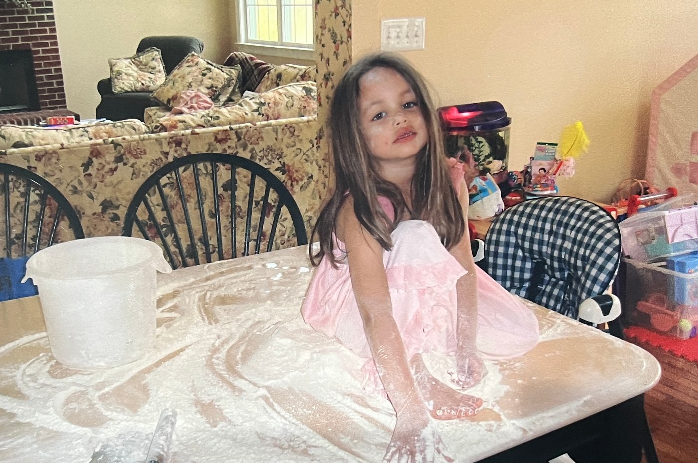 Lauren as a toddler, covered in flour on the kitchen table
